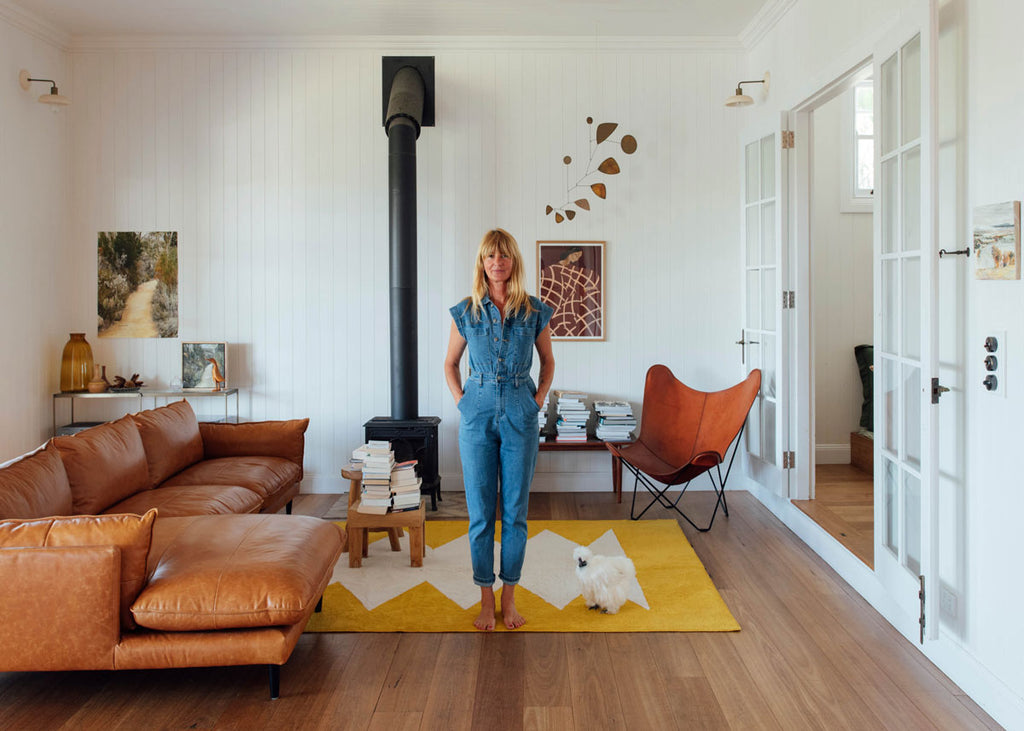 Yvonn Deitch wears blue overalls on a Double brand rug in her Byron Bay home