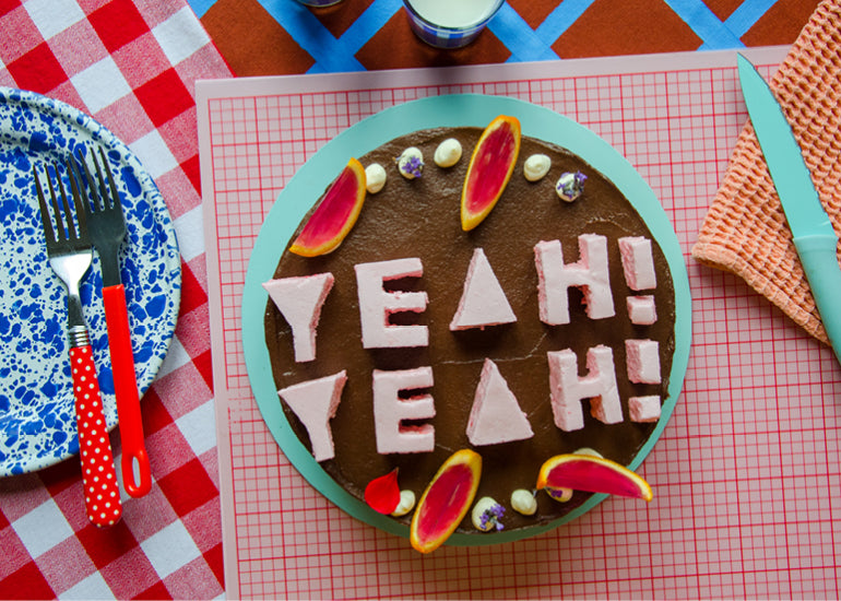 A cake with chocolate icing that says "Yeah! Yeah!" in pink marshmallow. Fun cake ideas.