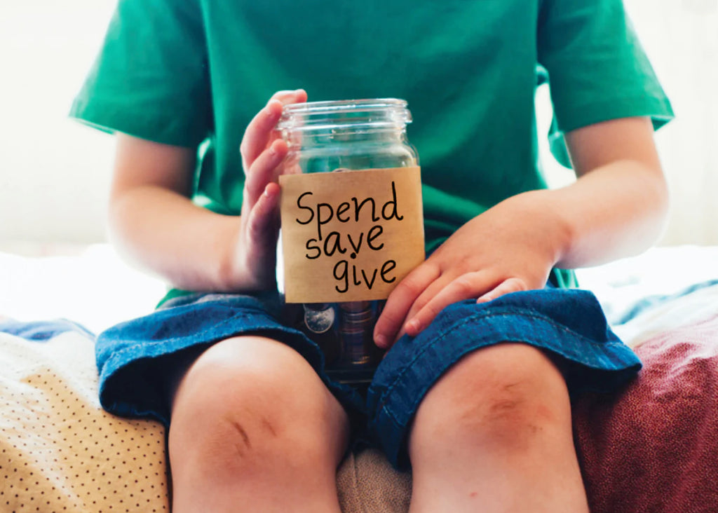 a child holds a jar that says ' spend save give' to teach gratitude for Lunch Lady Magazine