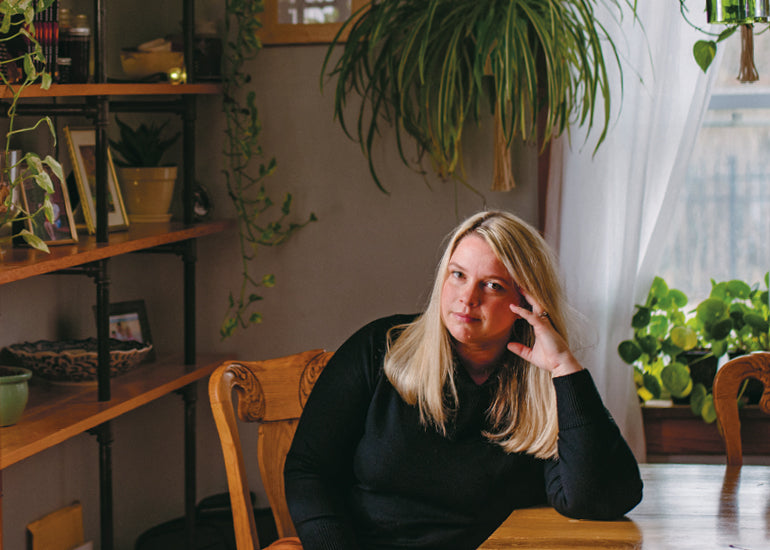 Kate Baer sits at a table wearing black for her Hello Lunchlady parenting interview