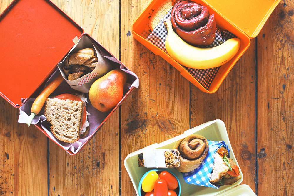 Three lunchboxes on a wooden table for Lunch Lady Magazine