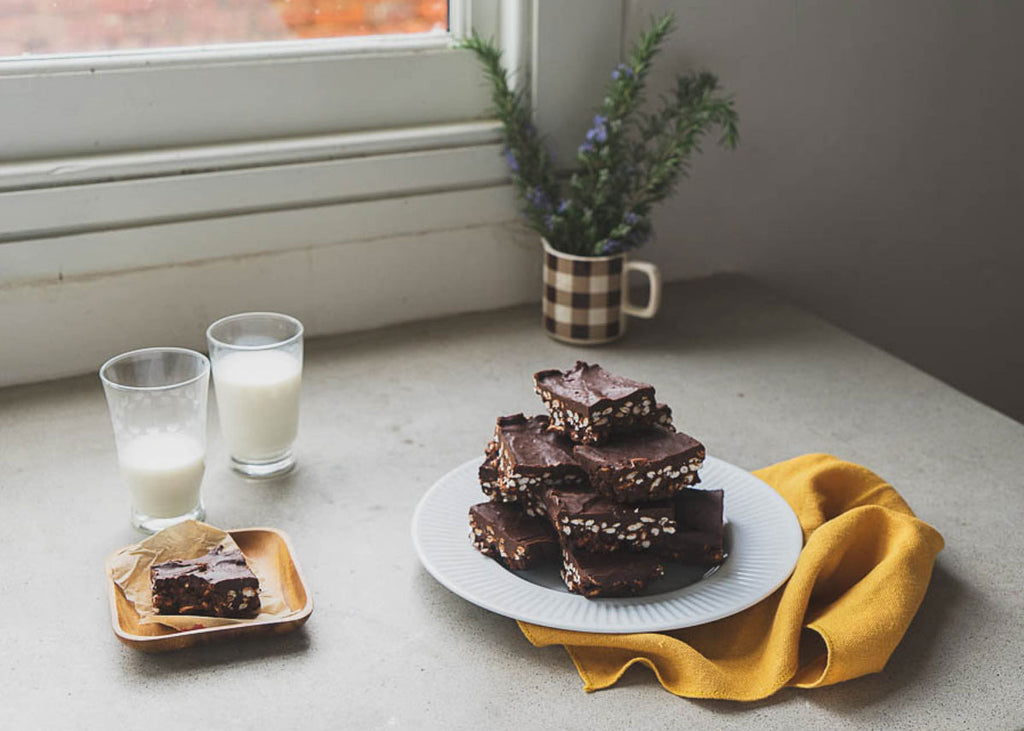 no-bake chocolate crackle slice on a plate beside a window with two glasses of milk