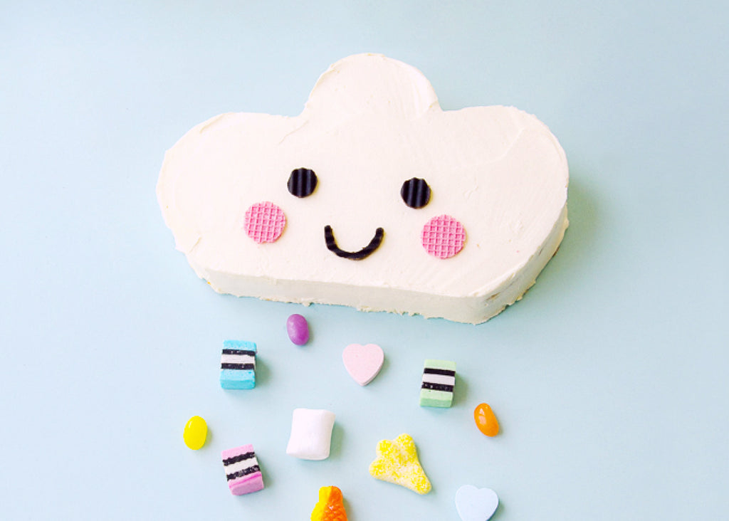 photo of a white cake shaped like a cloud with a smiley face and lolly raindrops for Lunch Lady Magazine