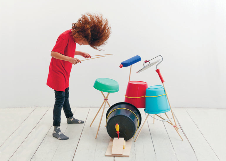 Photo of a boy flicking his hair while playing a homemade drum kit for Hello Lunch Lady Magazine